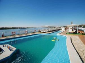 a large swimming pool next to a body of water at Nile Cruise Luxor & Aswoan Included balloon in Luxor