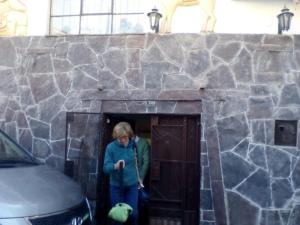 una mujer parada en una puerta en una pared de piedra en Wulzer Samana Wasi Andahuaylillas, en Andahuaylillas