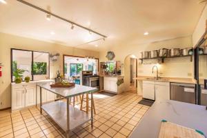 a large kitchen with a table in the middle at Gardenia Room on Tropical Lush Farm in Haiku, Maui in Huelo