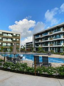 ein Swimmingpool mit Stühlen und einem Sonnenschirm und einem Gebäude in der Unterkunft Mana Beach Experience B 114, Porto de Galinhas in Porto De Galinhas
