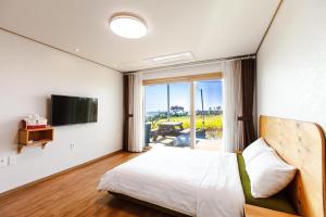 a bedroom with a bed and a television and a patio at Joyuam Jeju in Seogwipo