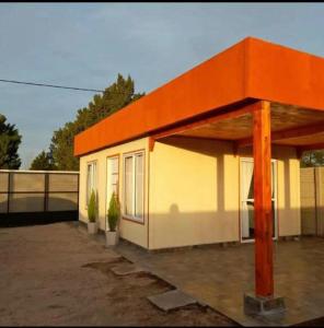 Cabañas Del Volga في Macachín: مبنى صغير بسقف برتقالي ونباتان