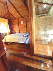 a bedroom with a bed and a toilet in a room at Paraiso Orquideario in Baños