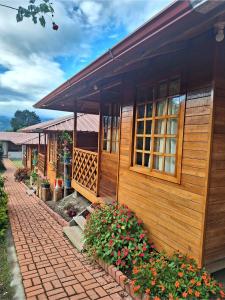 ein Holzhaus mit einem gemauerten Gehweg und Blumen in der Unterkunft Paraiso Orquideario in Baños