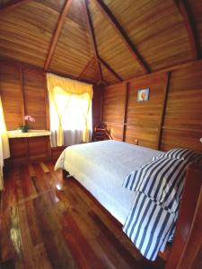 a bedroom with a bed in a room with a window at Paraiso Orquideario in Baños