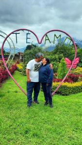 a couple kissing in front of a heart sign at Paraiso Orquideario in Baños