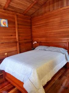 1 dormitorio con 1 cama en una habitación de madera en Paraiso Orquideario, en Baños