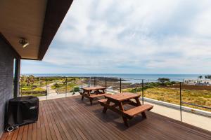 two picnic tables on a balcony with a view of the ocean at Joyuam Jeju in Seogwipo
