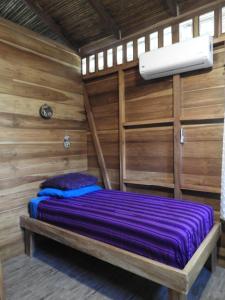 a bed in a room with wooden walls at Casita Bribri at Margarita Hills in Cocles