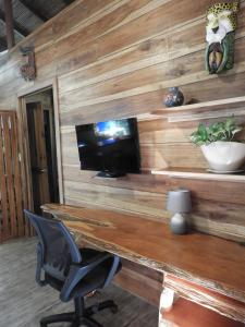 a wooden wall with a desk with a television and a chair at Casita Bribri at Margarita Hills in Cocles