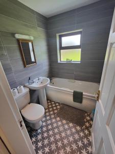 La salle de bains est pourvue de toilettes, d'un lavabo et d'une baignoire. dans l'établissement Old Killarney, à Killarney