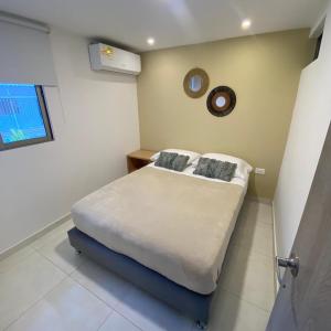 um quarto com uma cama e um relógio na parede em Aparta Suites Balcones de la Sierra em Fundación