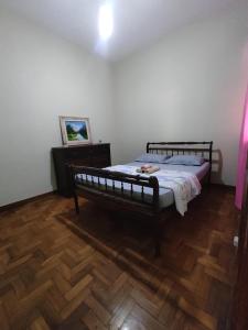 a bedroom with a bed and a wooden floor at Apartamento completo no centro in Teresópolis