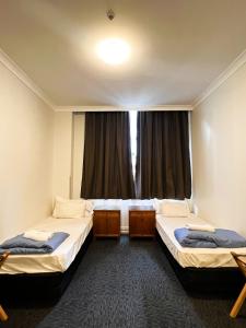 2 camas en una habitación con ventana en Fort Street Accommodation en Auckland