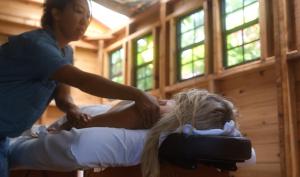 Eine Frau, die auf einem Bett sitzt und sich die Haare schneiden lässt. in der Unterkunft Plumeria Room on a Lush Farm on Maui's North Shore in Huelo