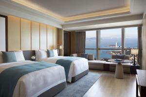 um quarto de hotel com duas camas e uma grande janela em The St. Regis Qingdao em Qingdao