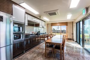 a large kitchen with a wooden table and chairs at Nadia Jeju in Jeju
