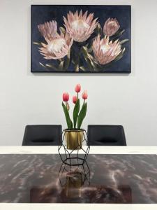 a vase with flowers on a table in front of a painting at Armadale Residence-Gala City in Kuching