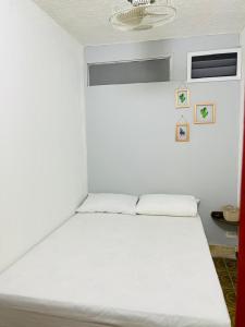 a white bed in a room with a window at HOSTAL AMA in Leticia