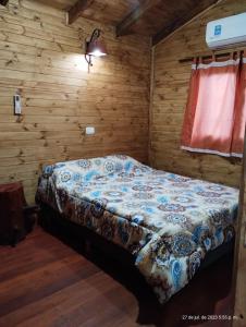 Un dormitorio con una cama en una cabaña de madera. en Cabañas Los Patricios, en Colón