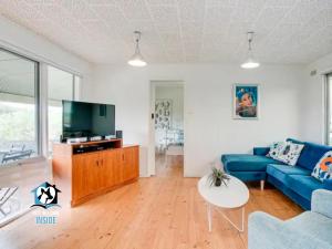 un soggiorno con un divano blu e una TV di Retro Groovy Pad Pt Elliot a Port Elliot