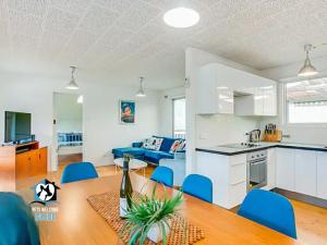 a kitchen and living room with a table and blue chairs at Retro Groovy Pad Pt Elliot in Port Elliot