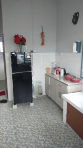 una cocina con nevera negra con un jarrón de rosas en IPOH Homestay, en Ipoh