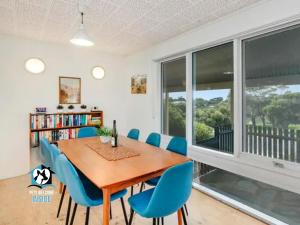 a dining room with a wooden table and blue chairs at Retro Groovy Pad Pt Elliot in Port Elliot