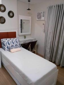Schlafzimmer mit einem Bett, einem Schreibtisch und einem Spiegel in der Unterkunft 2 BR Loop Tower 1524 in Cagayan de Oro