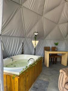 a yurt with a tub and a table in it at Refúgio Santa Helena - Domo Zen in Salesópolis