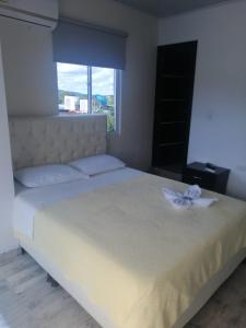 ein Schlafzimmer mit einem weißen Bett mit einer Blume darauf in der Unterkunft HOTEL LA CASONA in Tauramena