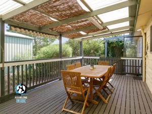 a patio with a wooden table and chairs on a deck at Retro Groovy Pad Pt Elliot in Port Elliot