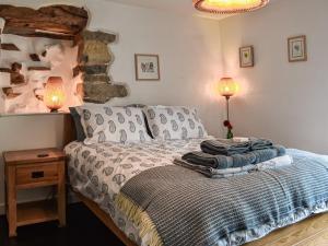 a bedroom with a bed with two lamps and a stone wall at Greystones in Ravenstonedale