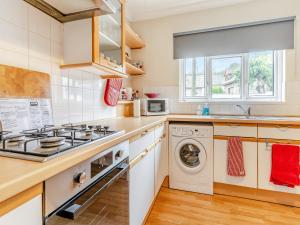a kitchen with a stove and a washer and dryer at Bradford House in Garnant