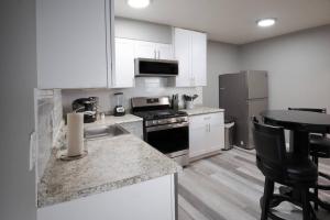 a kitchen with white cabinets and a stove and refrigerator at Luxurious 2-Bedroom Abode with Elevated Comforts Near Main Street in St. Charles