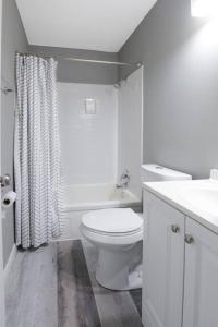 a white bathroom with a toilet and a sink at Luxurious 2-Bedroom Abode with Elevated Comforts Near Main Street in St. Charles