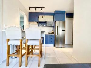 a kitchen with blue cabinets and two white chairs at Apartamento Espaçoso e Aconchegante na Bela Vista in São Paulo
