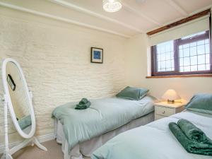 a bedroom with two beds and a mirror at The Nook in Saint Ewe