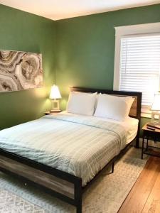 a bedroom with a bed with green walls and two lamps at The House Hotels - Cohasset Lower in Lakewood