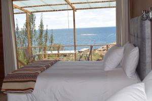 1 dormitorio con 1 cama y vistas al océano en Allpaluxe Peru Lodge en Ocosuyo
