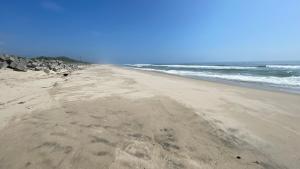 a beach with footprints in the sand and the ocean at ELM On The Beach in Kitaibaraki