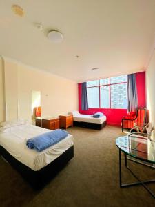 a hotel room with two beds and a glass table at Fort Street Accommodation in Auckland