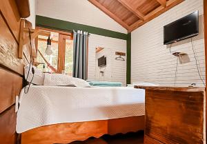een slaapkamer met een bed en een flatscreen-tv bij Chale pe na areia c WIFI -Praia do Peixe Grande BA in Prado