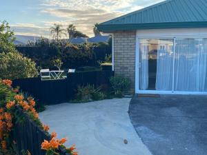 a house with a patio and a driveway at Pāpāmoa Beach Studio Oasis in Papamoa