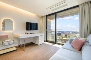 a living room with a couch and a desk with a television at IRO Jeju in Seogwipo