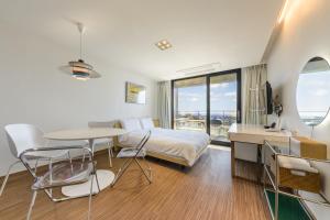a hotel room with a bed and a table and chairs at IRO Jeju in Seogwipo