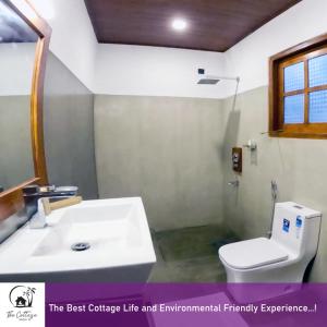 a bathroom with a white toilet and a sink at The Cottage Sigiriya in Sigiriya