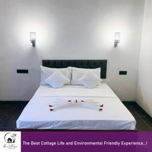 a bed with white sheets and decorations on it at The Cottage Sigiriya in Sigiriya