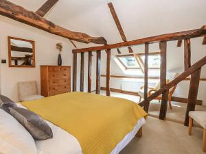 a bedroom with a bed with a yellow blanket at The Cottage Barn in Botesdale