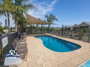 a swimming pool with chairs and a fence at Contemporary Golf Course Frontage 3BR in Normanville